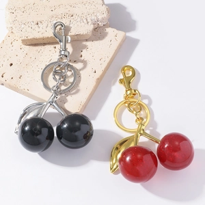 Creative resin cherry keychains with gold and silver metallic rings on stone podium