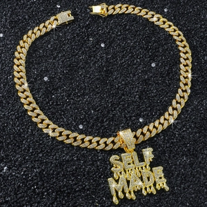 Macro shot of iced-out SELF MADE pendant with golden cuban chain on black background
