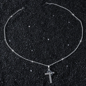 Macro detail of silver cross pendant with engraved scripture on a rope chain