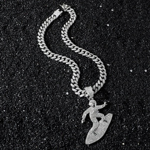 Silver iced out surfer pendant on cuban link chain with white stones over black stone background