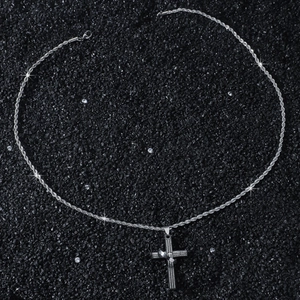 Detailed view of silver cross pendant with Spanish scripture and twisted rope chain