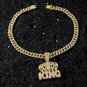 Gros plan du pendentif KING doré avec couronne et cristaux pavés sur chaîne Cubaine