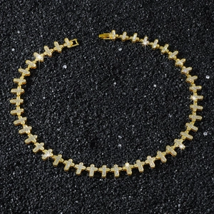 Macro shot of gold hip hop necklace featuring iced-out cross links on a dark sand background