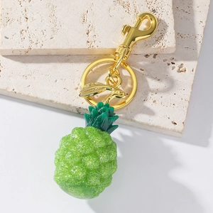 Close-up of a sparkling green resin pineapple keychain with a golden metal lobster clasp