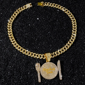 Macro shot of hip hop plate pendant with knife and fork details on cuban chain