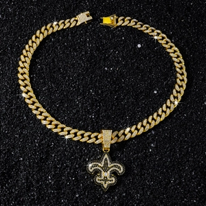 Detail der goldenen Panzerkette mit schwarz-weißem Fleur-de-lis Anhänger und Zirkonia