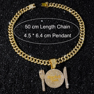 Detail view of iced-out hip hop plate and cutlery pendant with gold cuban chain