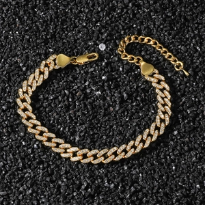Gold Cuban link anklet with shimmering rhinestones on dark stone backdrop