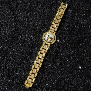 Gros plan d'un bracelet doré à maillons avec un médaillon de la Madone et des cristaux