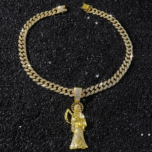 Macro view of iced-out gold Cuban chain with detailed Santa Muerte pendant on sand