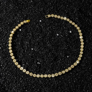 Gros plan du collier tennis doré avec zircons ronds sur un fond noir texturé