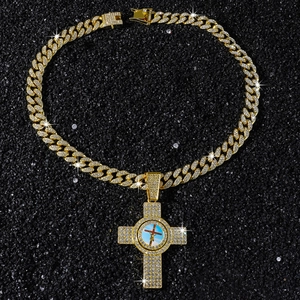 Macro shot of iced out Cuban link chain with gold Jesus cross pendant on black surface