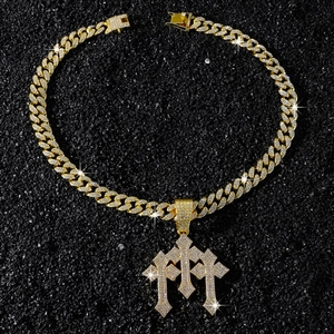 Close-up of gold iced out Cuban chain with triple gothic cross pendants on black stones