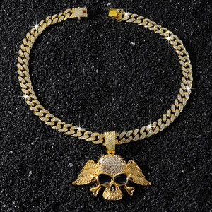 Macro shot of gold hip hop necklace with iced out winged skull pendant on black stones
