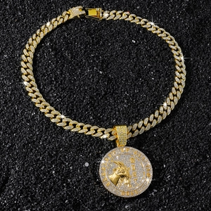 Macro shot of hip hop goat pendant necklace with sparkling rhinestones on black sand