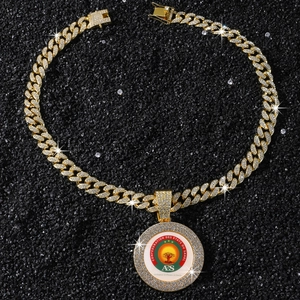 Gros plan du collier pendentif logo AES doré avec diamants sur fond de pierre noire texturée