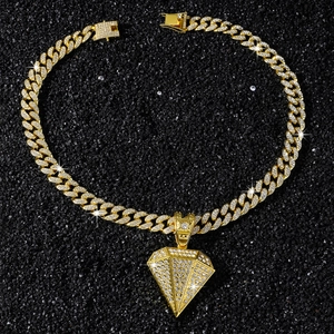 Close-up of hip hop gold Cuban link chain with iced out diamond pendant on black background