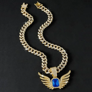 Macro shot of gold hip-hop pendant featuring a large blue gemstone and angel wings