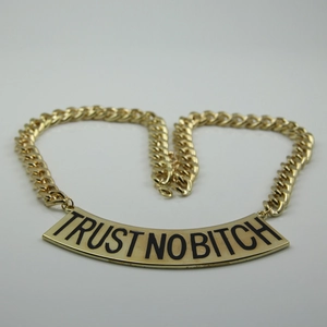 Détail du collier à grosse maille dorée avec pendentif gravé Trust No Bitch