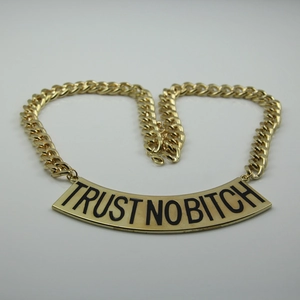 Détail du collier chaîne dorée avec plaque gravée noire TRUST NO BITCH style hip-hop
