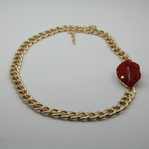 Détail macro du collier chaîne gourmette dorée avec pendentif lèvres en strass rouges