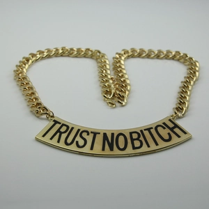 Détail du collier à grosse maille dorée avec pendentif à slogan TRUST NO BITCH