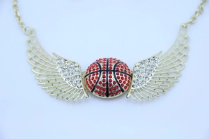 Macro del ciondolo a forma di basket con ali dorate e strass rossi e bianchi brillanti