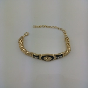 Detail of gold snake chain bracelet featuring lion head relief and sparkling rhinestones
