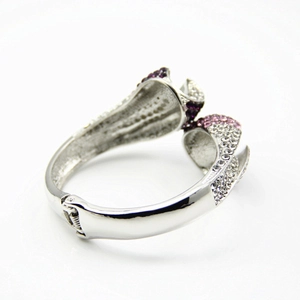 Détail d'un bracelet à charnière argenté avec fleurs serties de strass violets et roses