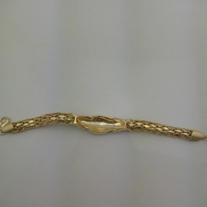 Macro detail of golden snake chain bracelet featuring intricate mesh texture and lobster clasp