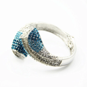 Détail d'un bracelet jonc argenté serti de strass blancs et dégradés de bleu