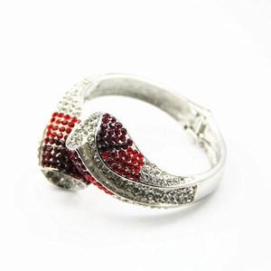 Détail d'un bracelet à charnière en alliage argenté avec strass rouges et blancs sur fond blanc