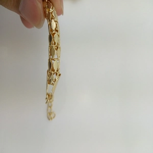 Detailed view of golden metal link bracelet with textured openwork design and extender chain