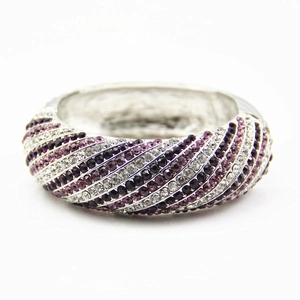 Exaggerated silver bangle featuring diagonal stripes of purple and clear rhinestones