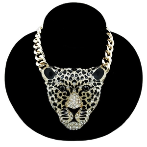 Detail of a large gold leopard head necklace encrusted with white rhinestones on a black bust