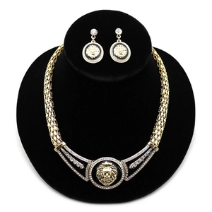 Detailansicht des Löwenkopf-Schmucksets mit goldener Kette und Ohrringen auf schwarzem Ständer