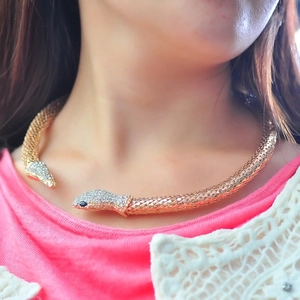 Détail du collier ras de cou serpent doré avec cristaux blancs et yeux en pierre noire