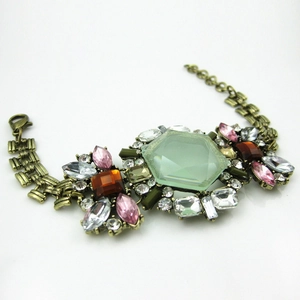 Detail of vintage bronze alloy floral bracelet with large green hexagonal crystal and gems