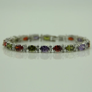 Detail view of colorful oval gemstones set in a silver bracelet with brilliant white zircons
