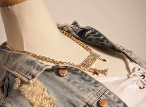 Detail of chunky gold chain necklace with rhinestone PARIS letter charms and Eiffel Tower