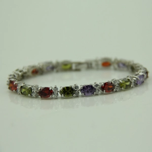 Detailed close-up of a silver bracelet featuring oval red, green, and purple gemstones