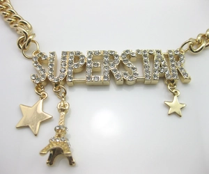 Detailed macro view of golden Superstar pendant with rhinestones and Eiffel Tower charms