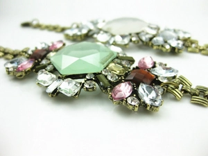 Detailed macro of vintage bronze floral bracelet with large green gemstone and pink crystals