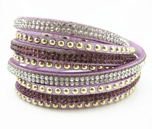 Dettaglio di bracciale avvolgente in velluto viola con strass e rivetti dorati