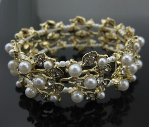 Detailed close-up of gold leaf bracelet featuring pearls and rhinestones on black base