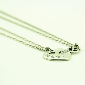 Vue macro de deux pendentifs en forme de cœur argenté gravés Best Friends