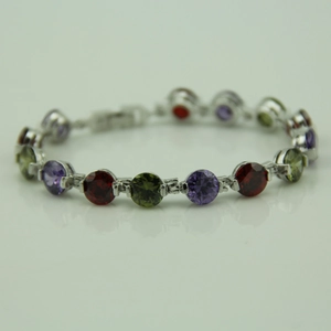 Detail showing round-cut purple, red, and green gemstones on a silver chain bracelet