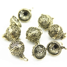 Detail of vintage bronze hollow orb pendant with intricate floral pattern and clasp