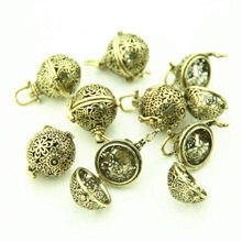 Detailed view of vintage bronze hollow filigree cage pendants for DIY jewelry