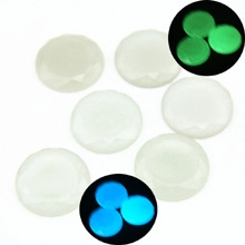 Luminous faceted round gems showing blue and green glow effects in dark background